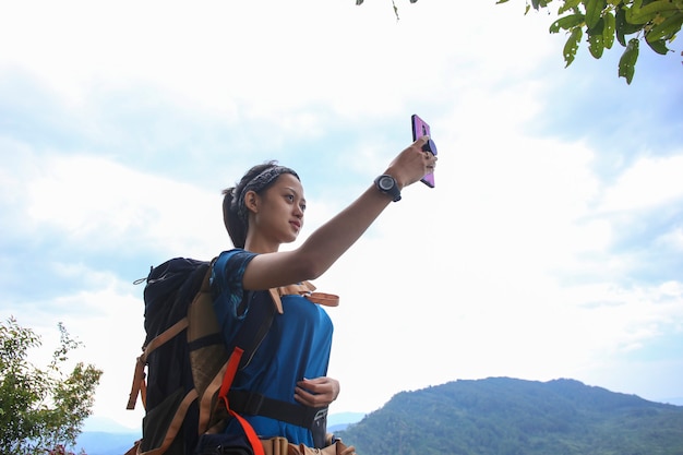 Une femme touristique utilise un smartphone dans les montagnes