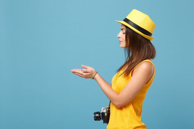 femme touristique en vêtements décontractés d'été jaune et chapeau avec appareil photo sur bleu