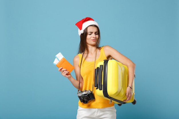 Femme touristique voyageur en bonnet de Noel, vêtements décontractés jaunes tenant un sac de billets appareil photo sur bleu