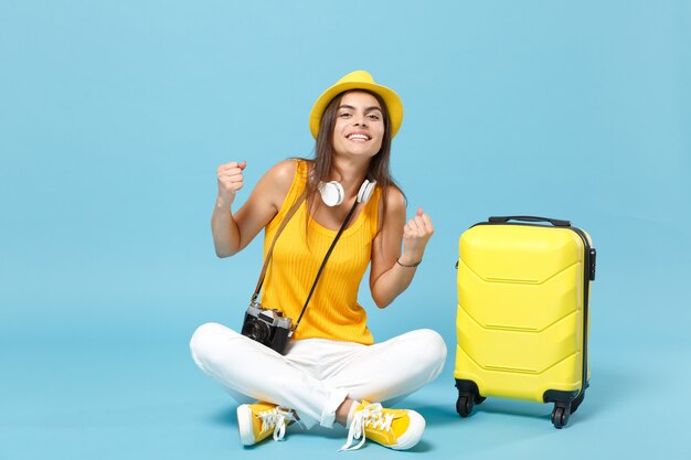 Femme touristique voyageur en vêtements décontractés jaunes, chapeau avec appareil photo valise sur bleu