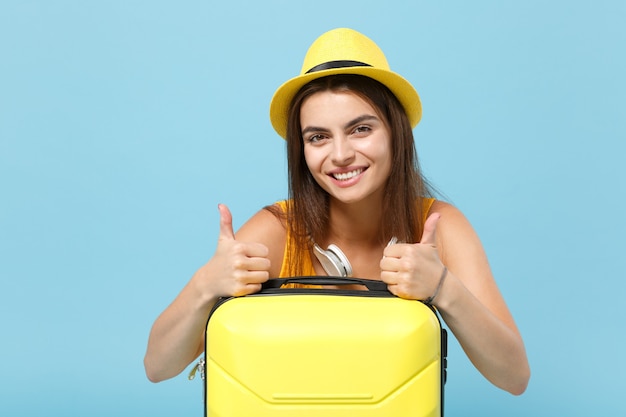 Femme touristique voyageur en vêtements décontractés jaunes, chapeau avec appareil photo valise sur bleu