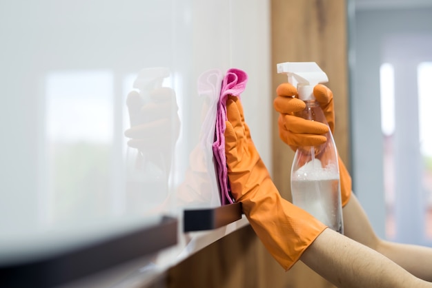 Femme tout en nettoyant la surface d'un bureau de cuisine avec une éponge dans ses gants en caoutchouc. travaux ménagers