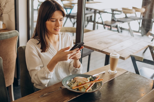 Femme en train de déjeuner dans un café, manger de la salade