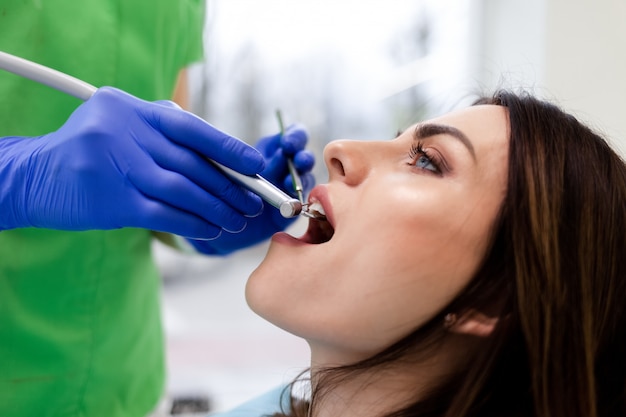 Femme traite des dents à la clinique dentaire. Un dentiste utilise une perceuse pour percer les dents des patients