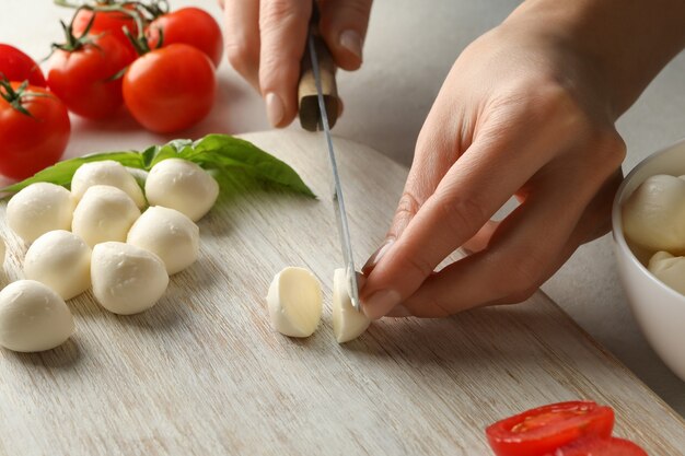 Femme tranchant la mozzarella sur une planche à découper