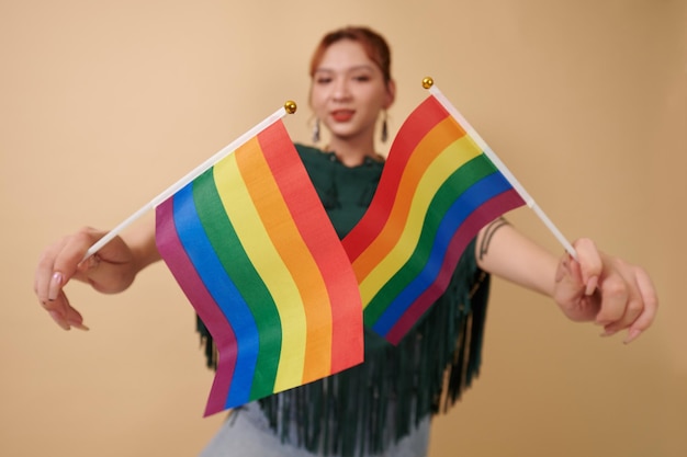 Photo femme transgenre excitée tenant deux drapeaux arc-en-ciel