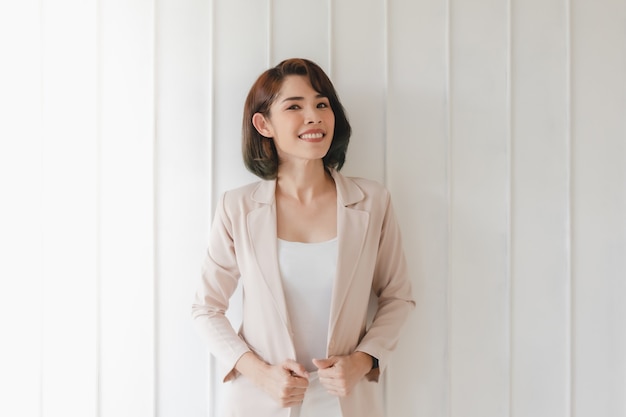 Femme de travail asiatique confiante en blazer beige isolé sur blanc