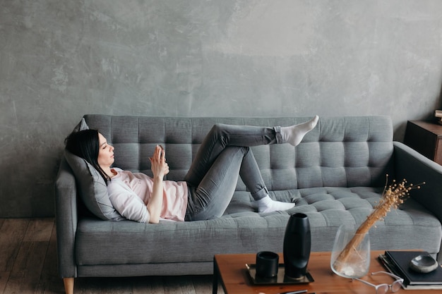 Photo femme travaillant comme influenceuse des médias sociaux allongée sur un canapé à la maison