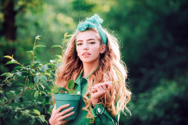 Femme travaillant dans un beau jardin vert femme tenant un pot de fleur