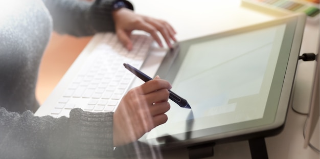 Femme travaillant dans un bureau créatif à l'aide d'une tablette à dessin