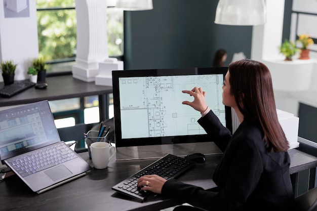 Femme travaillant dans un logiciel de rédaction immobilière, zoomant sur le plan du projet, concevant l'intérieur dans la vue arrière de l'application de créateur 2d. Cad, plans sur écran d'ordinateur, plan d'étage de la salle du designer