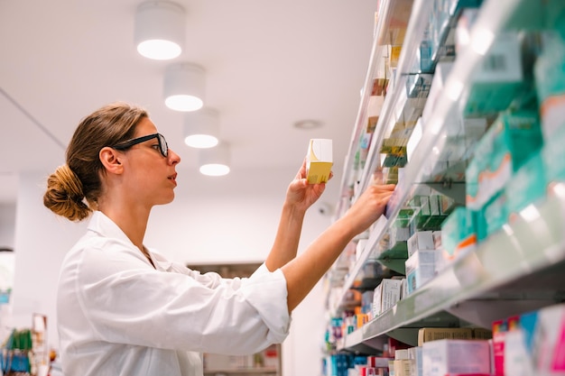 La femme travaillant dans la pharmacie recherche la médecine