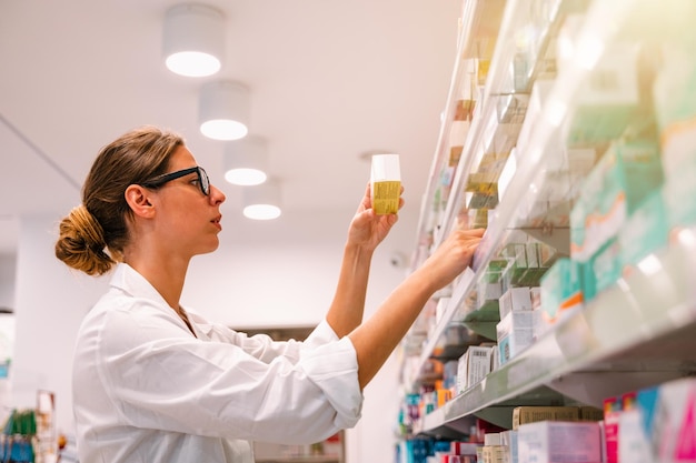 La femme travaillant dans la pharmacie recherche la médecine
