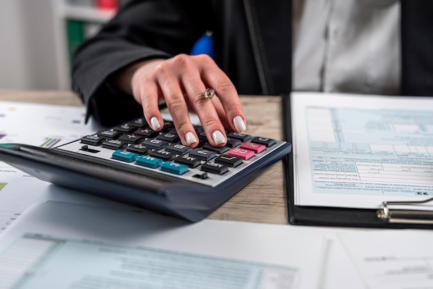 Femme travaillant avec un document de rapport d'entreprise remplissant un formulaire fiscal temps comptable pour l'impôt