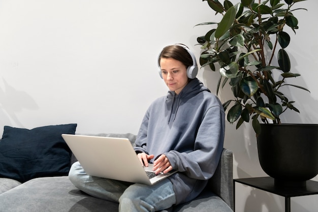 Femme travaillant à domicile sur le canapé avec ordinateur portable