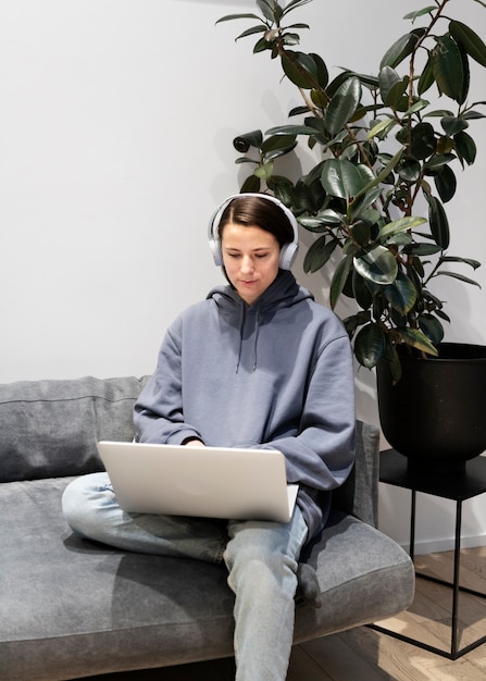 Femme travaillant à domicile sur le canapé avec ordinateur portable