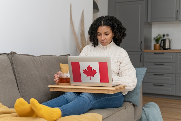 Femme travaillant à domicile sur un ordinateur portable avec le drapeau canadien