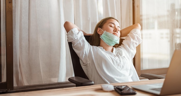 Une femme travaillant à domicile portant un masque de protection attend que la situation épidémique s'améliore bientôt à la maison. Coronavirus, covid-19, Travail à domicile (WFH), Distanciation sociale, Quarantaine, Concept de prévention des infections.