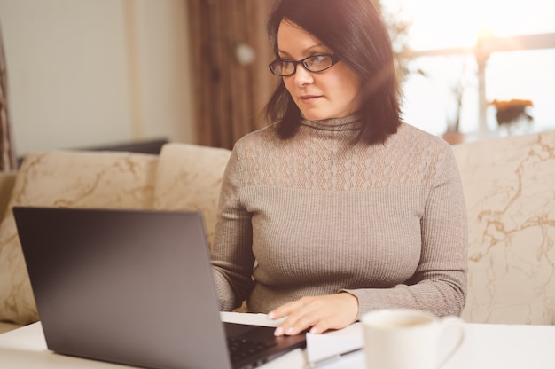 Femme travaillant à la maison regardant un webinaire en ligne sur une formation commerciale sur un ordinateur portable travaillant à distance