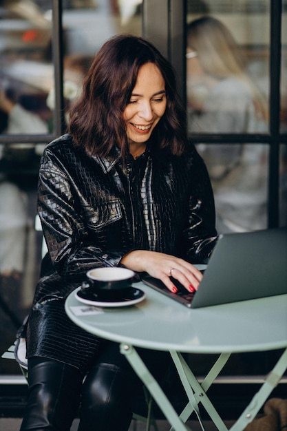 Femme travaillant sur ordinateur dans un café et buvant du café