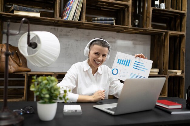 Une femme travaillant sur un ordinateur portable à l'aide d'un casque dans un casque montre un graphique à l'écran
