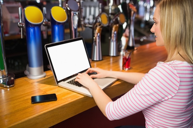 Femme travaillant sur ordinateur portable au bar comptoir