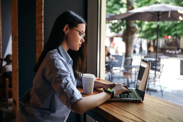 Femme travaillant avec un ordinateur portable dans le café