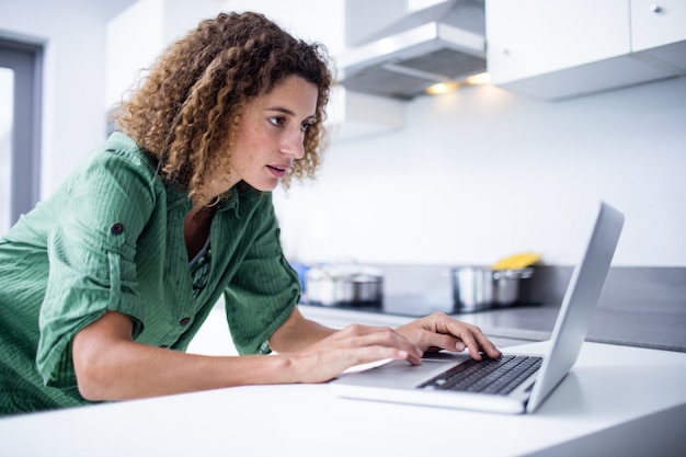 Femme travaillant sur un ordinateur portable dans la cuisine