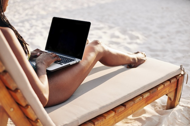 Femme travaillant sur ordinateur portable sur la plage