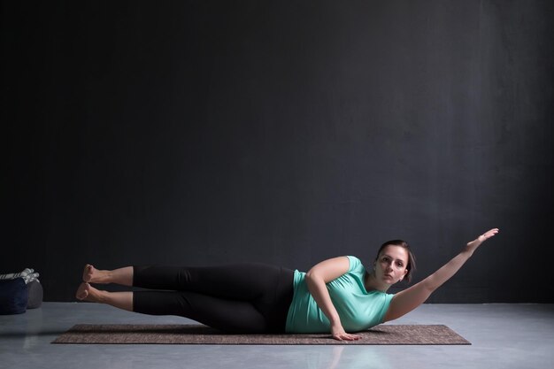 Femme travaillant sur son corps latéral faisant une variation de planche latérale