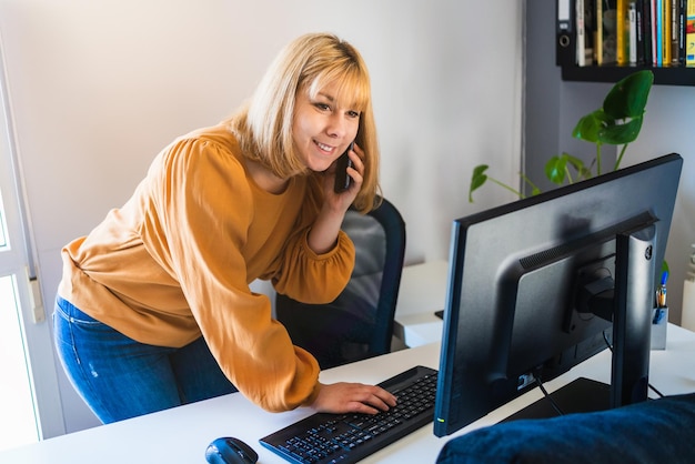 Femme travaillant souriante debout devant un ordinateur de bureau au bureau