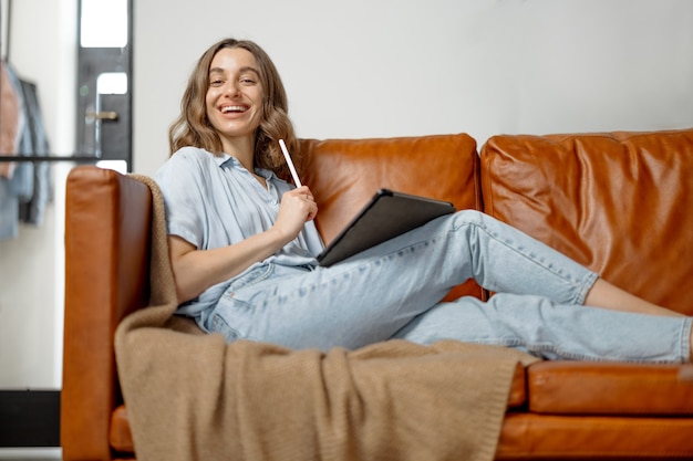 Femme travaillant avec une tablette numérique depuis la maison sur un canapé