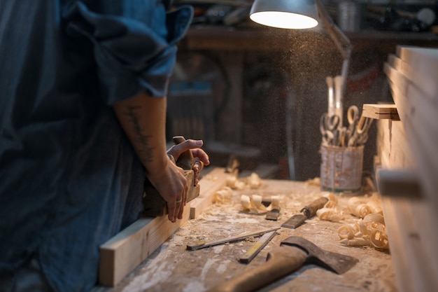 La femme travaille dans un atelier avec un bois. Menuisier d'outils