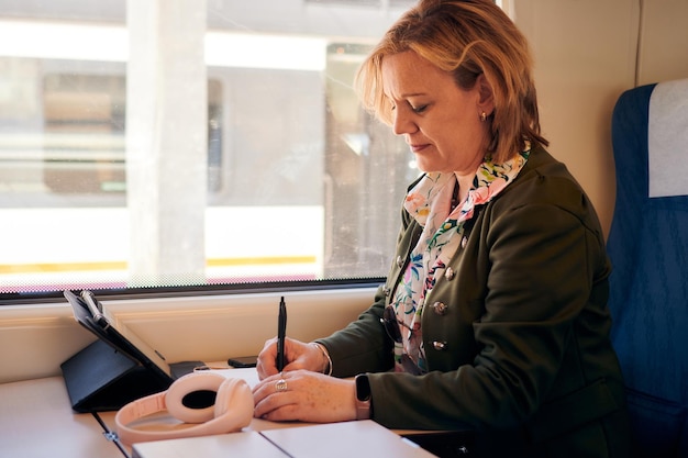 Une femme travaille dans un train avec une tablette et un ordinateur portable