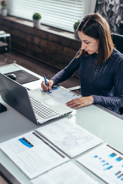 Une femme travaille avec des documents assis à table.