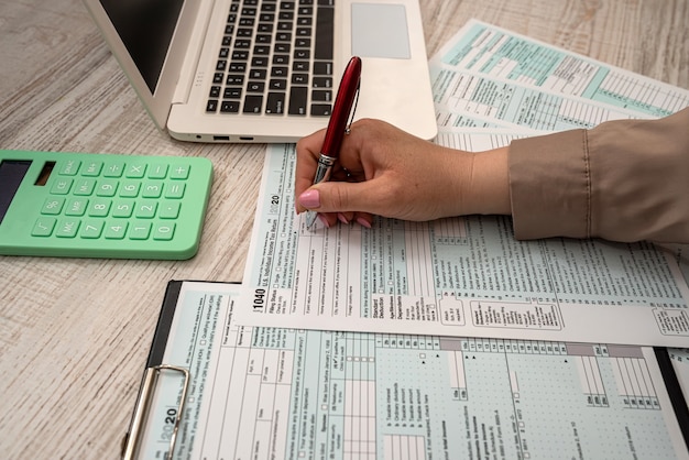 Une femme travaille avec le formulaire fiscal américain 1040 et un ordinateur portable au bureau. Notion de comptabilité