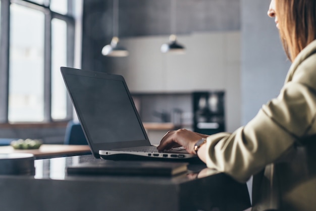 Femme travaille à la maison assis à son bureau avec son ordinateur portable