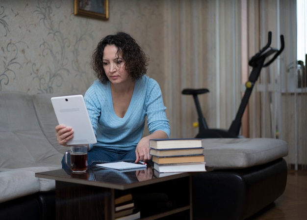 Une femme travaille à la maison derrière une tablette.