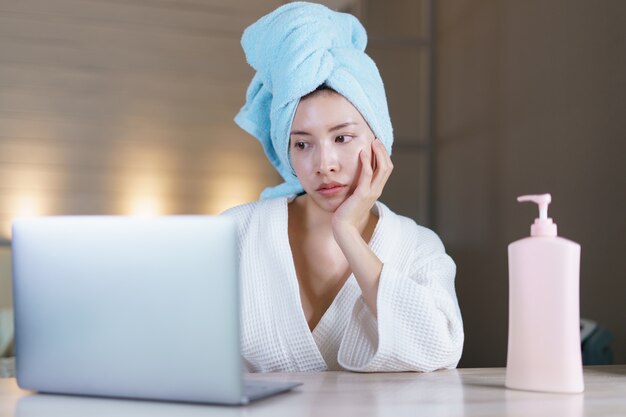 Femme travaille de la maison en quarantaine portant un masque de protection et se nettoyant les mains avec un gel désinfectant