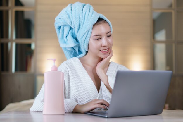 Femme travaille de la maison en quarantaine portant un masque de protection et se nettoyant les mains avec un gel désinfectant