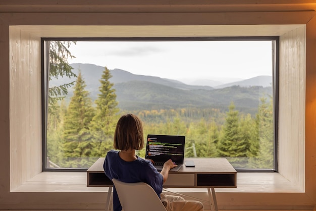 Femme travaille sur ordinateur portable à distance dans la maison sur la nature