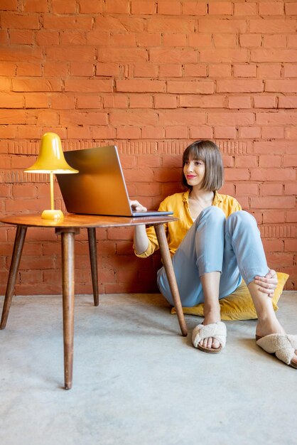 La femme travaille sur l'ordinateur portable à la maison