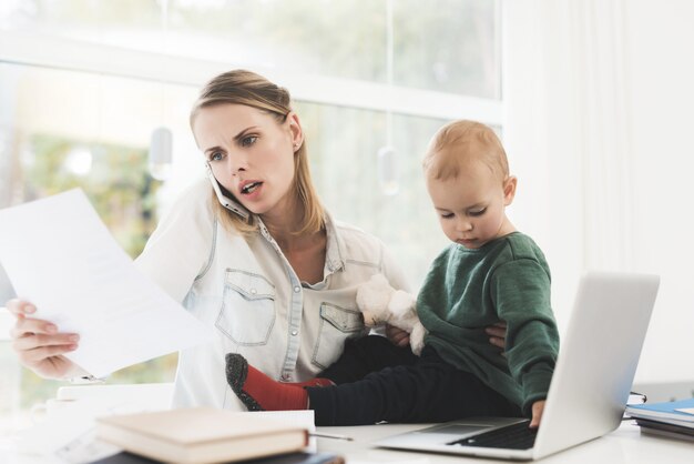 Une femme travaille et s&#39;occupe d&#39;un enfant en même temps.