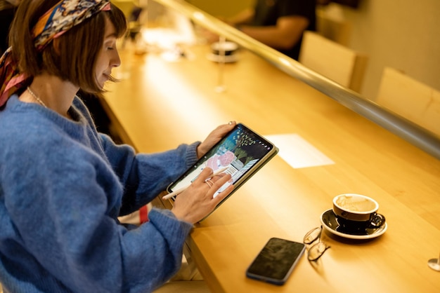 Femme travaille sur touchpad au café