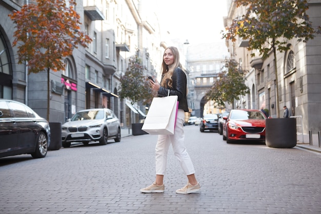 Femme traversant la route en centre-ville, portant des sacs à provisions