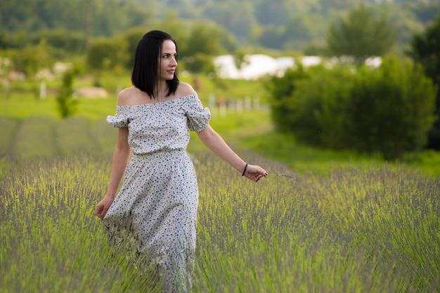 Une femme traverse un champ d'herbes hautes.