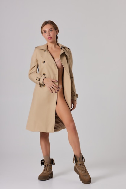 Femme en trench-coat et sous-vêtements en studio