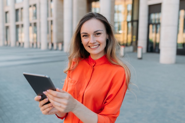 Femme trentenaire tenant une tablette électronique.