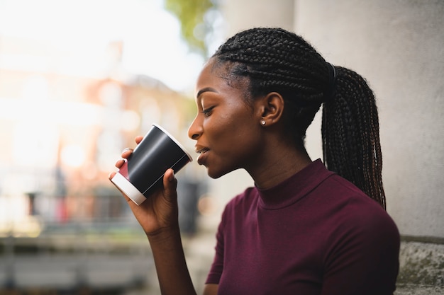 Femme avec des tresses ayant une tasse de café chaud