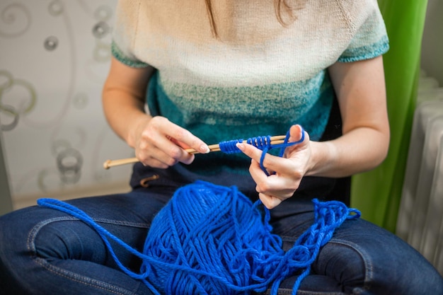 Femme tricotant un pull en fil bleu